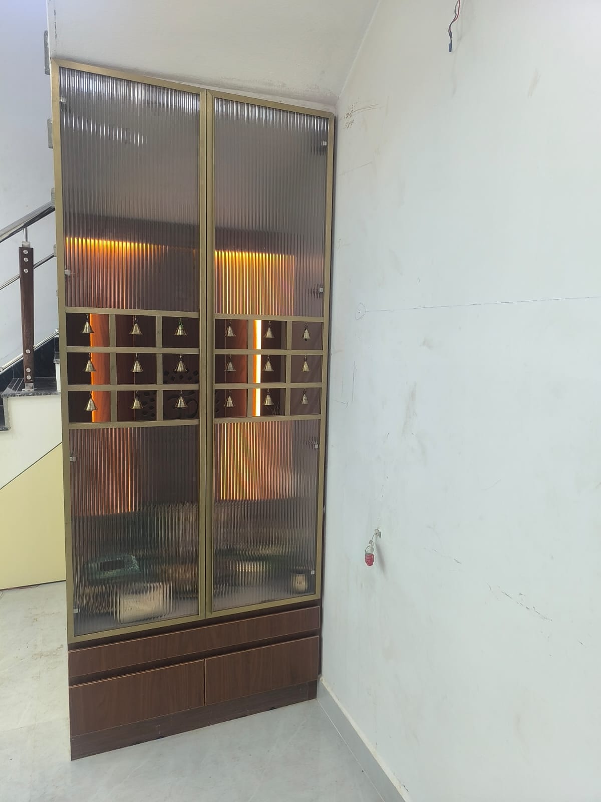 Tall pooja cabinet with fluted glass and bells